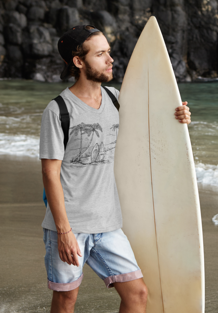 Man holding a surfboard wearing a Fetch The Swell coastal graphic T-shirt